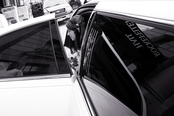 black and white photo of the bride arriving at the ceremony location, Rockefeller Hall, in a limousine with the location's sign reflected in the window - photo by Houston based wedding photographer Adam Nyholt 